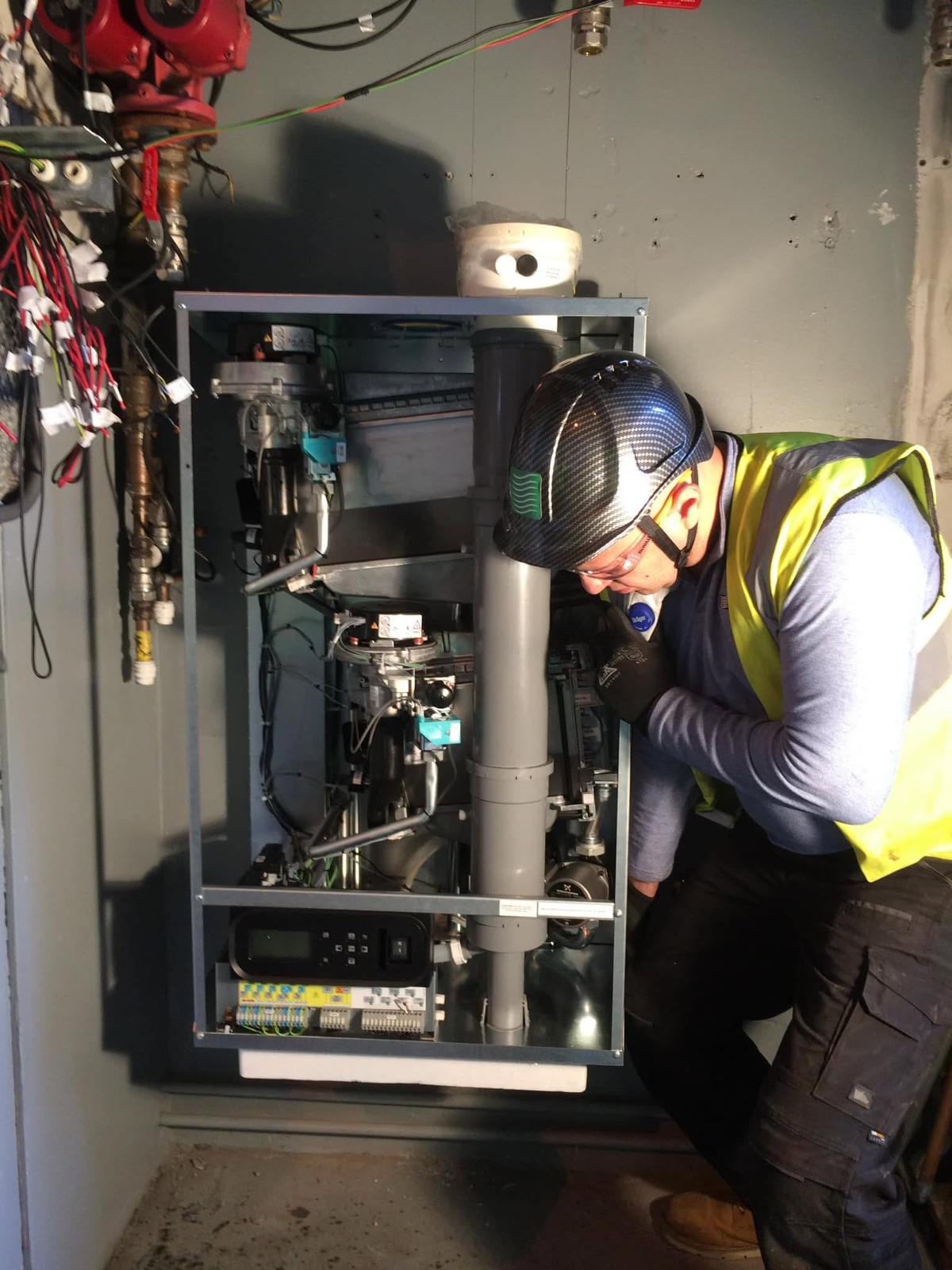 Engineer carrying out commissioning checks on a wall-hung boiler with the casing off
